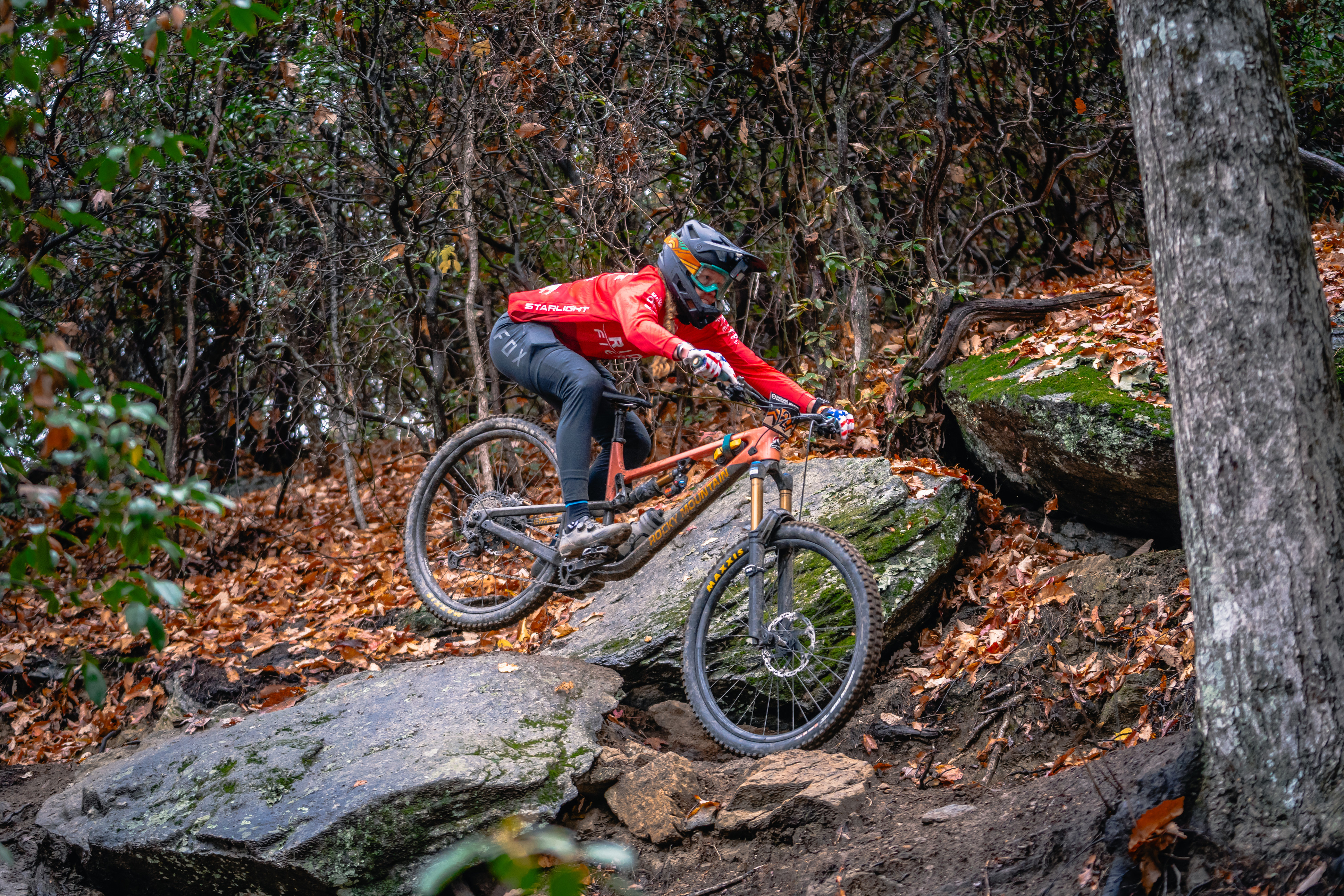 Abigail Snyder on mountain bike racing through wooded and rocky terrain