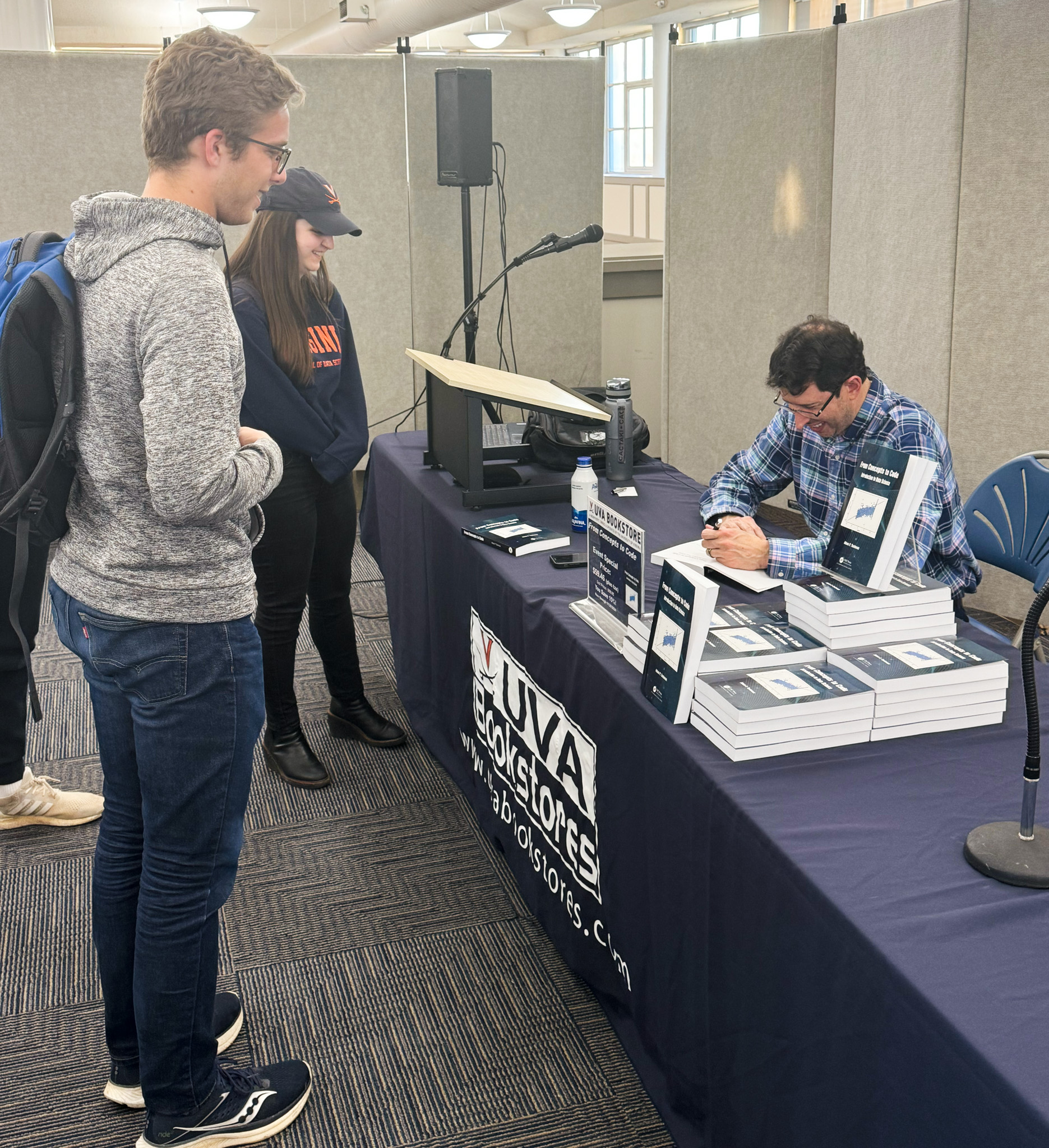 Professor Adam Tashman smiles while signing a book for a student.