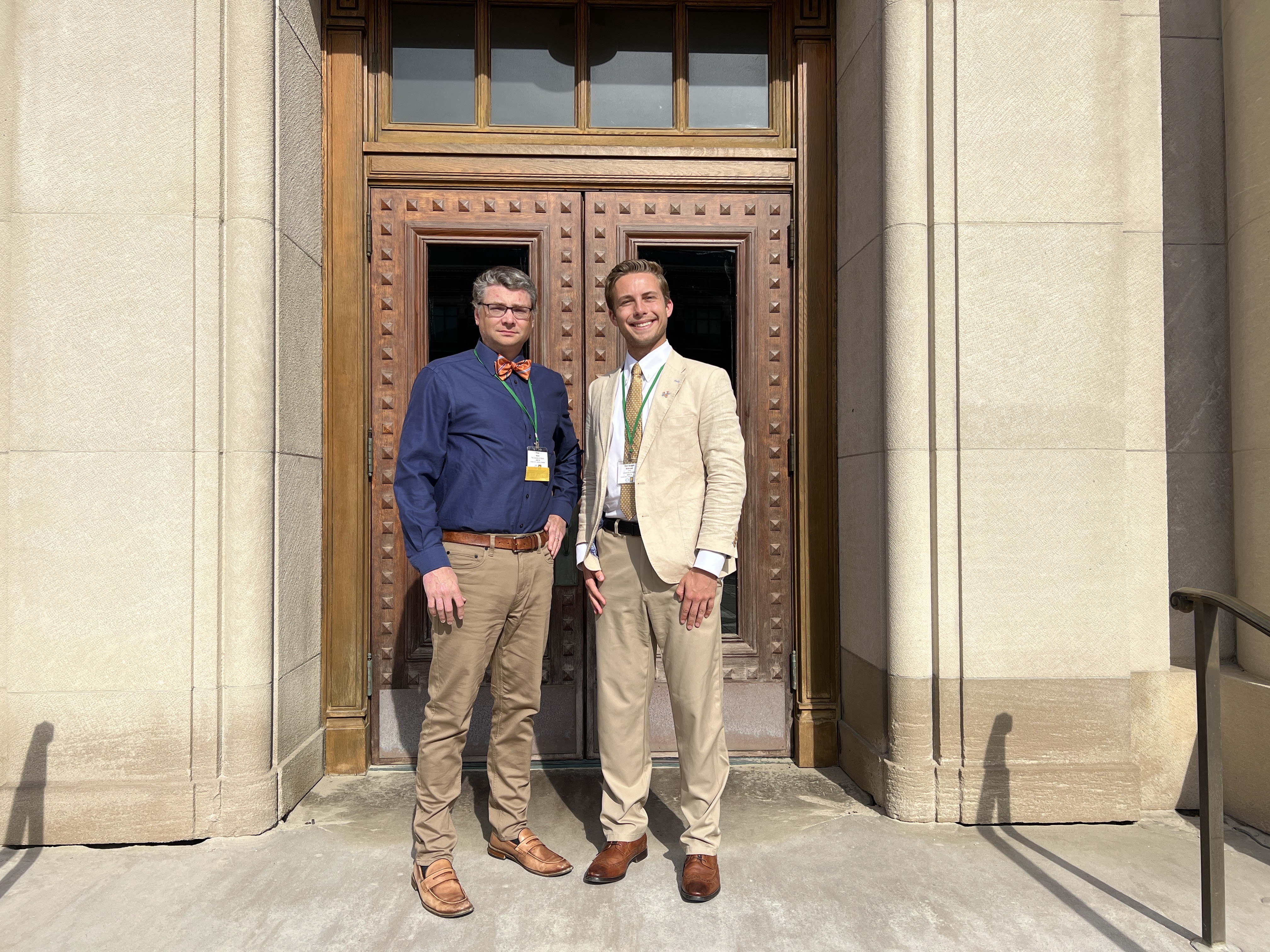 UVA Data Science Professor Pete Alonzi and MSDS student Finn Mokrzycki posing outside in front of a building