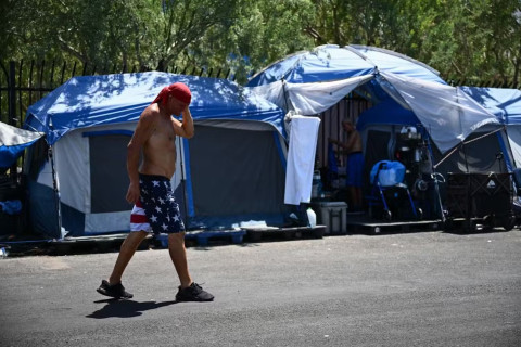 A man walks in front of tents at a homeless encampment