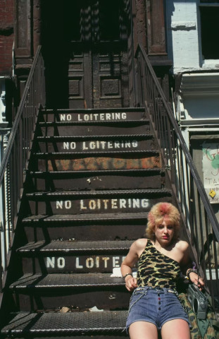 Person sitting on stairs marked no loitering