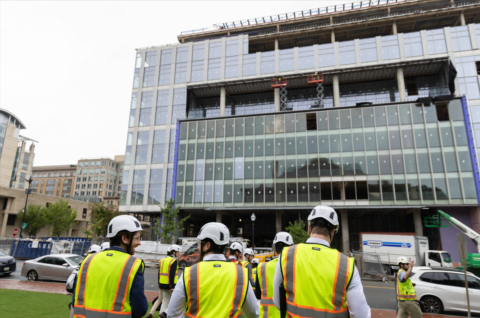 People wearing safety vests and hard hats walk towards a construction area.