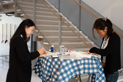 Rachel Seo and another BSDS student paint canvas bags inside of the School of Data Science.