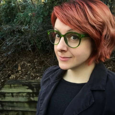 Photo of Mar Hicks wearing a black jacket and green glasses while standing in an outdoor area.