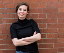 Mona Sloane standing in front of a brick wall with her arms crossed.