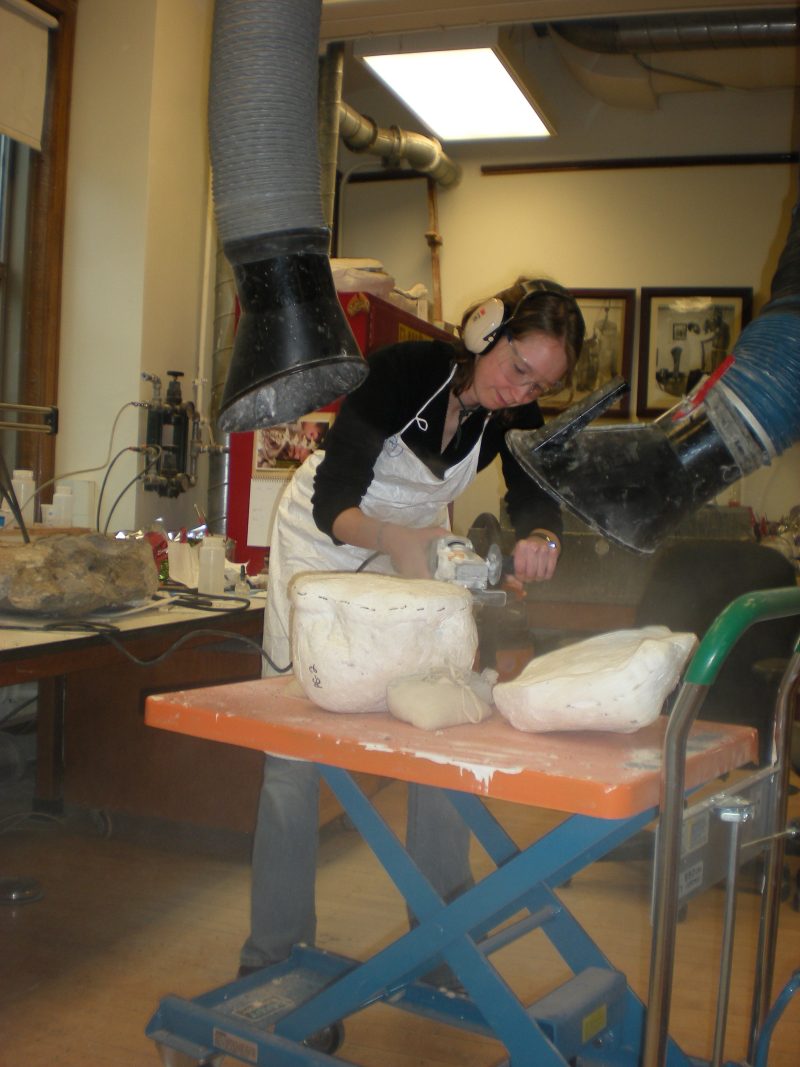 Caitlin Wylie using a vacuum to prepare a dinosaur fossil
