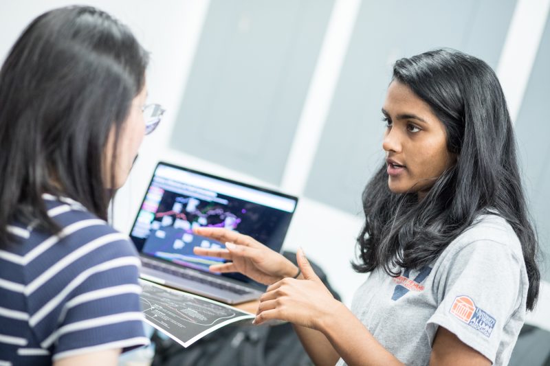 Two women discussing data around a computer