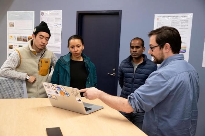 Jon Kropko and students discuss data science around a laptop