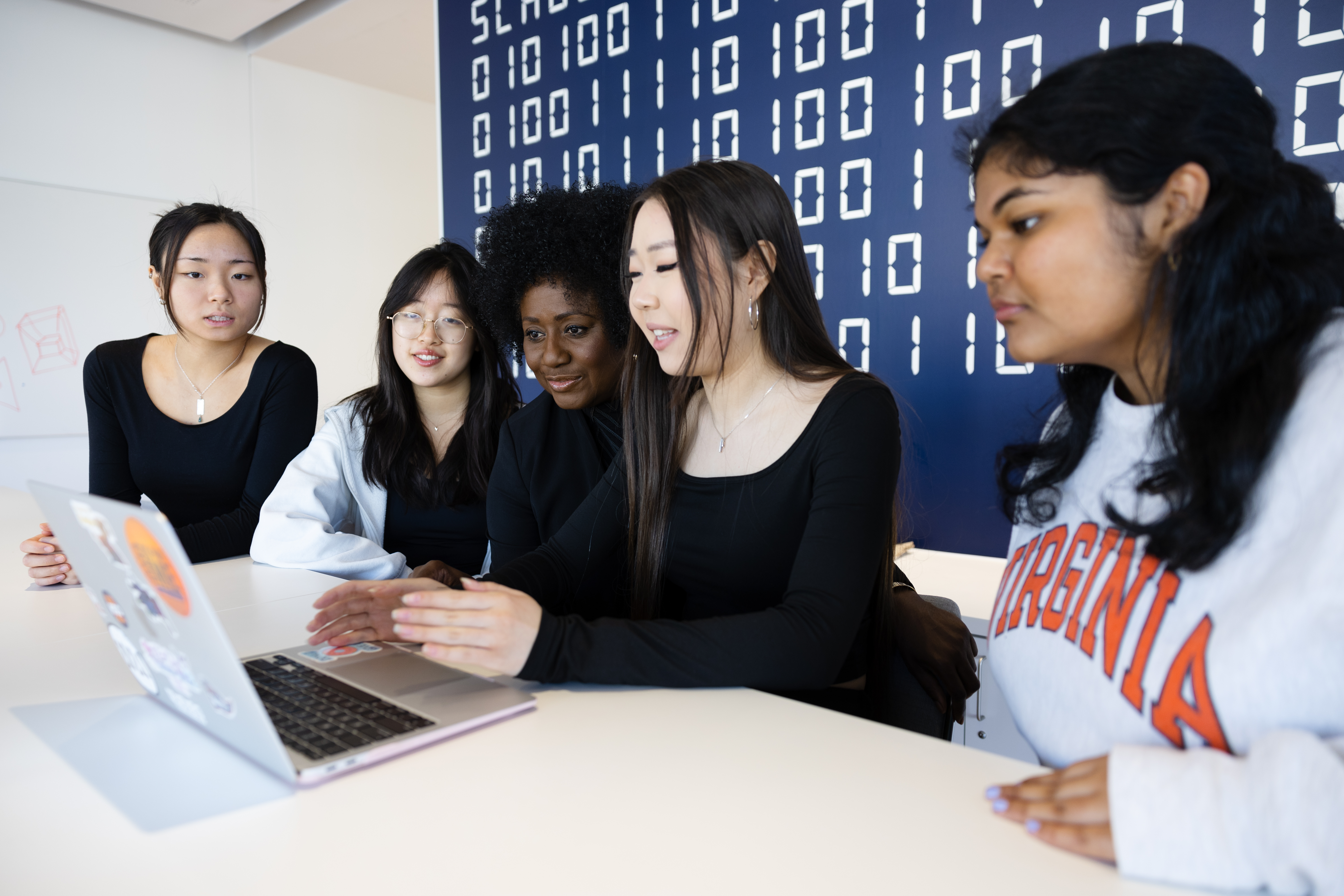 UVA Data Science BSDS Students with Professor around laptop with binary code wall behind it