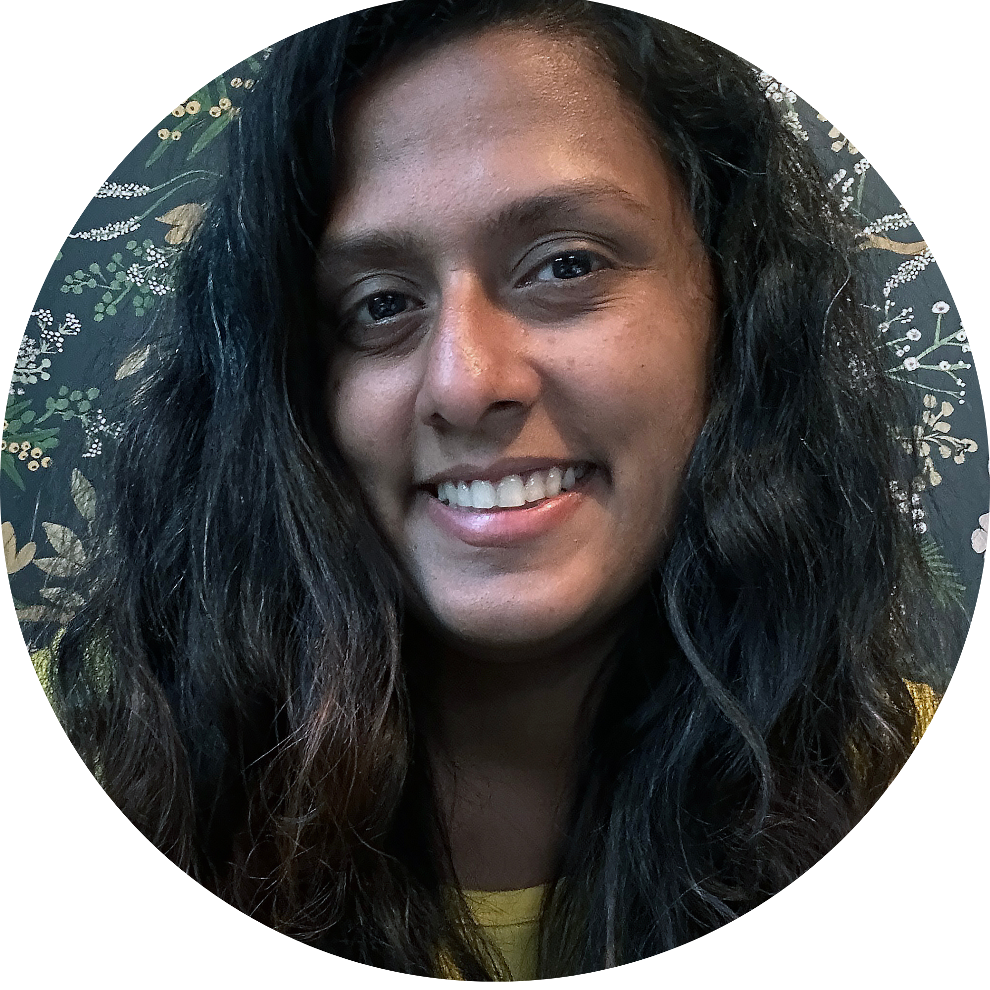 Headshot of Padmini Chandrasekaran smiling in front of a floral wallpaper. 