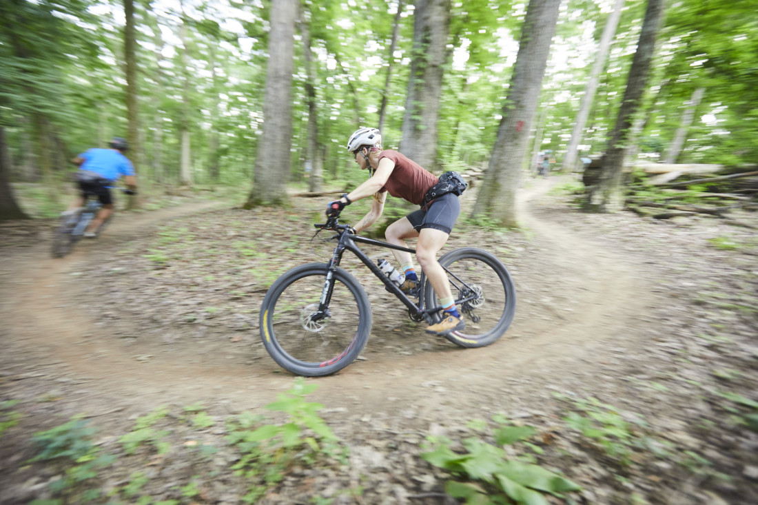 Abigail Snyder mountain bike racing on a curvy trail in the woods