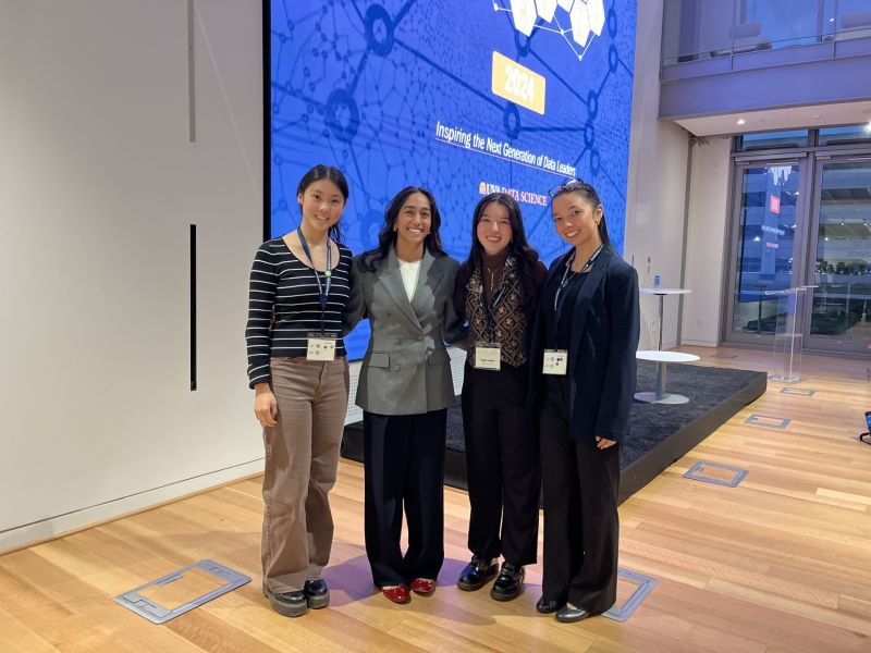 Kayla poses with Miriam Friedel and two other friends in the School of Data Science's Capital One Hub.