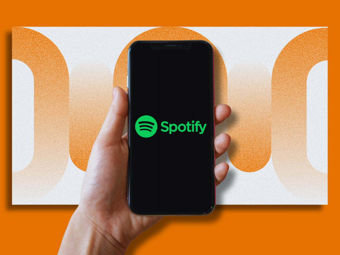 Graphic of a person's hand holding an iPhone with the Spotify logo on a display screen. The background features an abstract orange design.