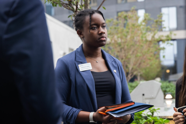 Courtney Hodge holding her notebook and listening intently in an outdoor setting.