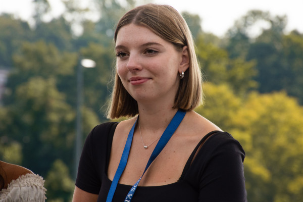 A close up photo of Madeleine Cummings standing on the terrace of the UVA School of Data Science. Bright greenery is behind her. 