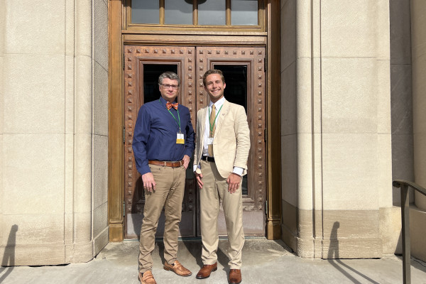 UVA Data Science Professor Pete Alonzi and MSDS student Finn Mokrzycki posing outside in front of a building