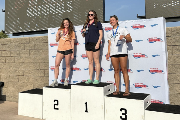 Elizabeth Miller poses on the second place podium step with other swimmers.